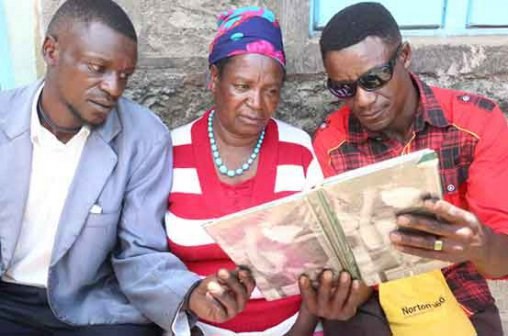Family members of Nancy Muthoni Munene (centre) go through some photos of her son David Muchoki Munene, one of the victims of Mandera attack, at Chaka Village, Nyeri County. News of the death of Munene has left his family in shock. (PHOTO: KIBATA KIHU/ STANDARD)